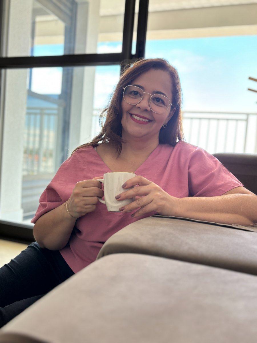 Silvane Abreu sentada com uma xícara nas mãos, em ambiente de luz natural.
